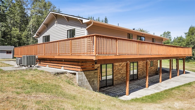 rear view of property with central air condition unit, a yard, and a wooden deck