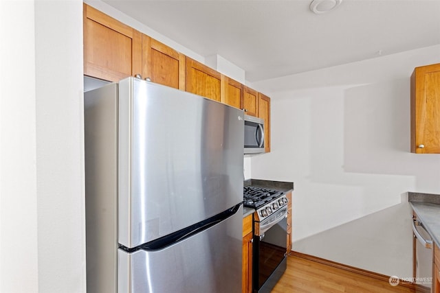 kitchen with light hardwood / wood-style floors and appliances with stainless steel finishes