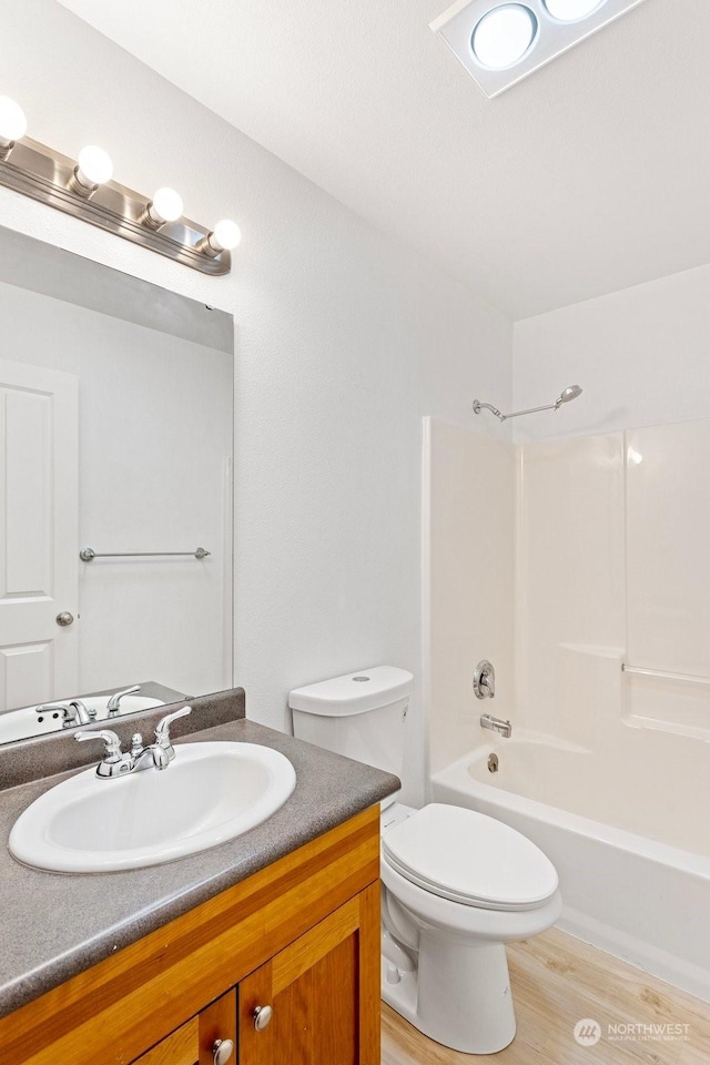 full bathroom with hardwood / wood-style flooring, shower / tub combination, vanity, and toilet