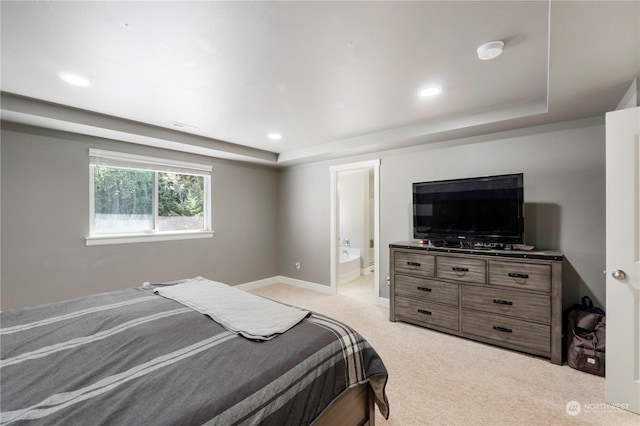 carpeted bedroom with ensuite bath and a raised ceiling