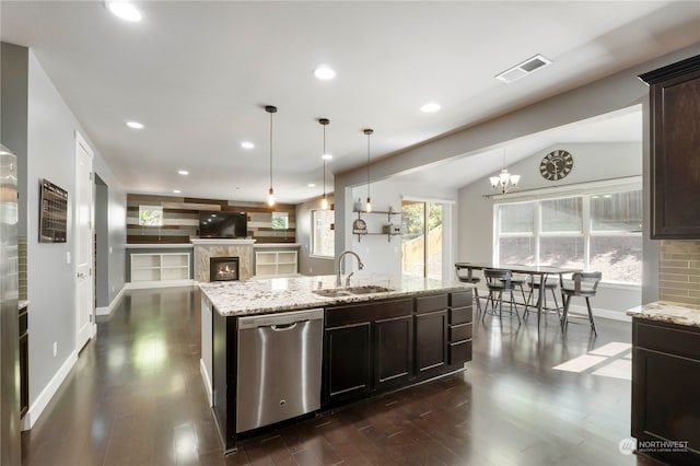 kitchen featuring dark wood-type flooring, an island with sink, stainless steel dishwasher, vaulted ceiling, and sink