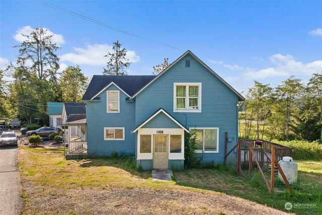 front facade with a deck and a front lawn