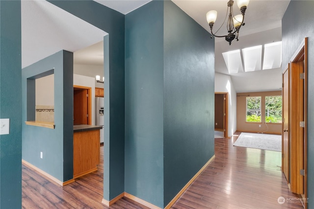 hall featuring lofted ceiling, dark wood-type flooring, and a notable chandelier