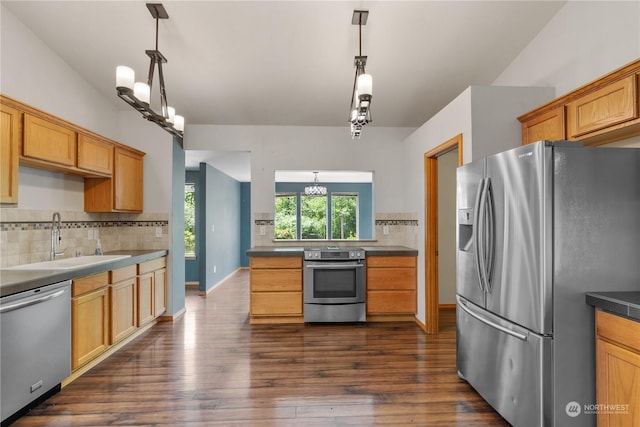 kitchen featuring appliances with stainless steel finishes, tasteful backsplash, dark wood-type flooring, hanging light fixtures, and sink