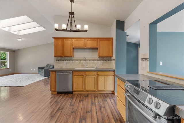 kitchen featuring backsplash, lofted ceiling with skylight, sink, dark wood-type flooring, and appliances with stainless steel finishes