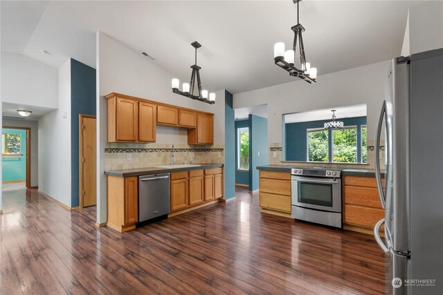 kitchen featuring stainless steel appliances, backsplash, lofted ceiling, pendant lighting, and sink