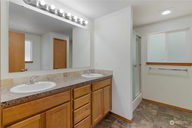 bathroom featuring a shower with door and vanity