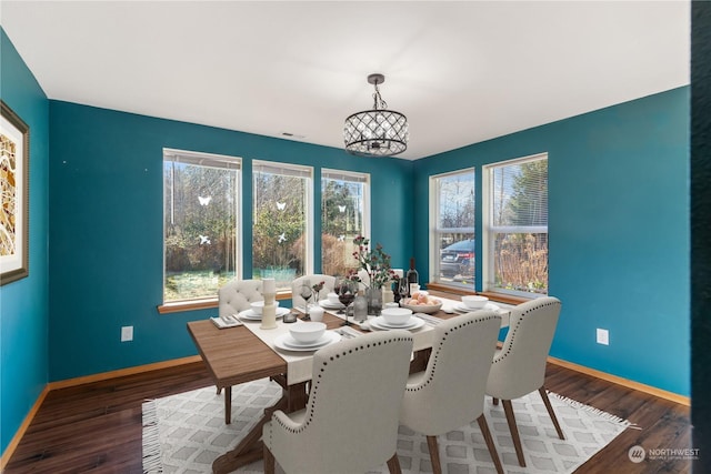 dining space featuring dark wood-type flooring and a notable chandelier