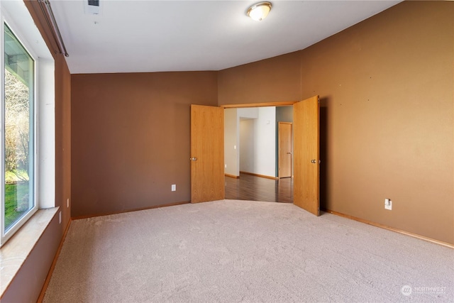 spare room with carpet floors and lofted ceiling