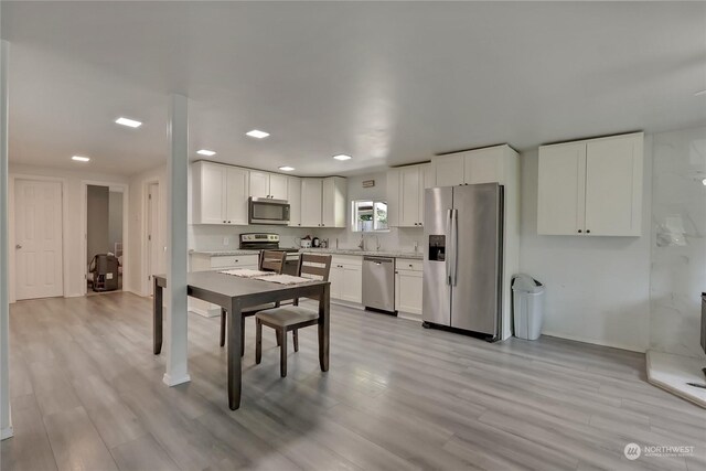 kitchen with sink, white cabinetry, stainless steel appliances, and light hardwood / wood-style floors