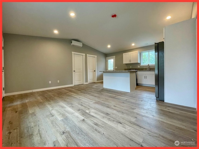 kitchen featuring a wall mounted air conditioner, light wood-style flooring, open floor plan, and freestanding refrigerator