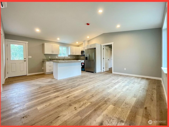 kitchen featuring lofted ceiling, a sink, appliances with stainless steel finishes, white cabinetry, and light wood-type flooring
