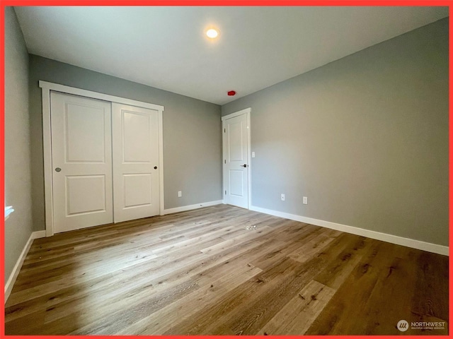 unfurnished bedroom with a closet, baseboards, and wood finished floors