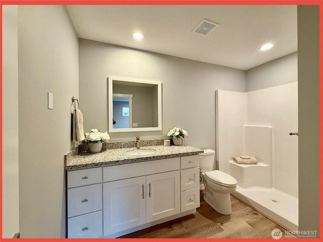full bath with visible vents, walk in shower, toilet, wood finished floors, and vanity