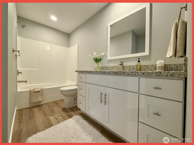 full bath featuring bathing tub / shower combination, toilet, wood finished floors, and vanity