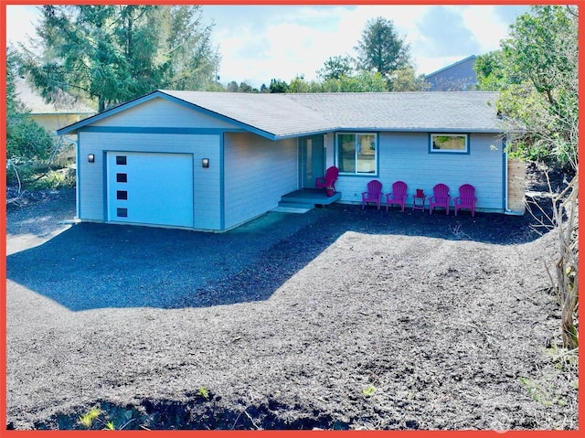 single story home featuring an attached garage and gravel driveway