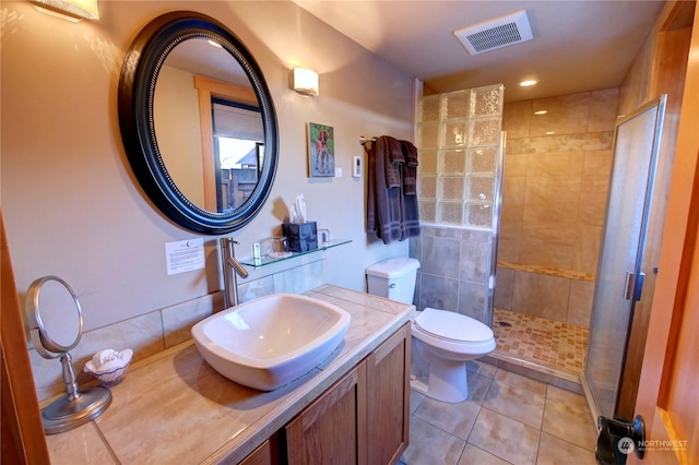 bathroom featuring tile patterned floors, vanity, a tile shower, and toilet