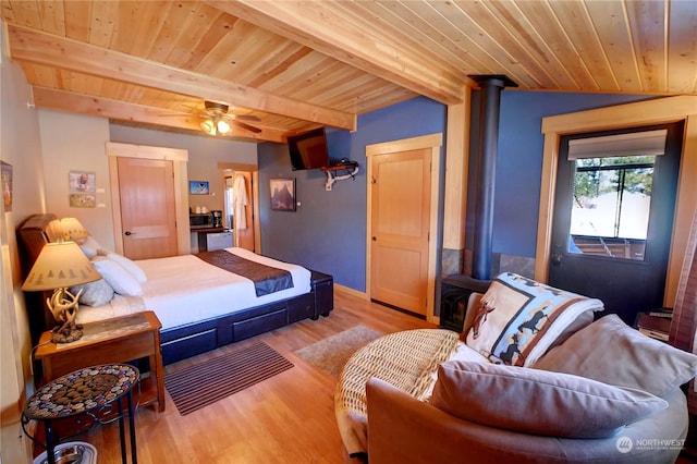 bedroom with ceiling fan, beam ceiling, light wood-type flooring, wood ceiling, and a wood stove