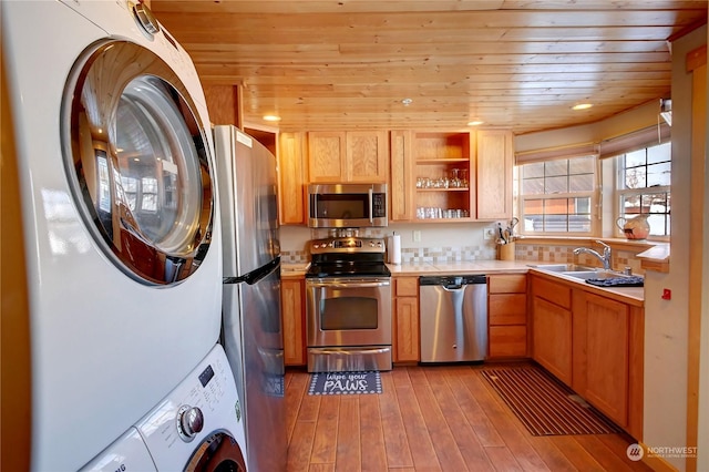 kitchen with stacked washing maching and dryer, appliances with stainless steel finishes, sink, and wooden ceiling