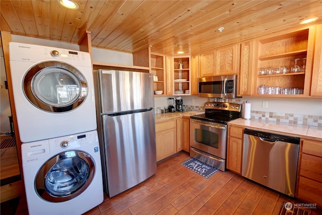 kitchen featuring stacked washer / dryer, appliances with stainless steel finishes, light hardwood / wood-style floors, and wooden ceiling