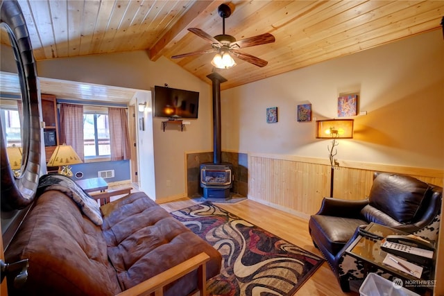 living room featuring ceiling fan, wood walls, light hardwood / wood-style floors, a wood stove, and wooden ceiling