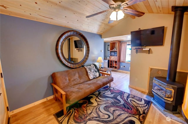 living room featuring wooden ceiling, ceiling fan, a wood stove, light wood-type flooring, and vaulted ceiling