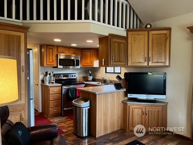 kitchen with dark wood-type flooring, high vaulted ceiling, and stainless steel appliances