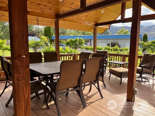 sunroom with lofted ceiling with beams, a healthy amount of sunlight, a mountain view, and wooden ceiling