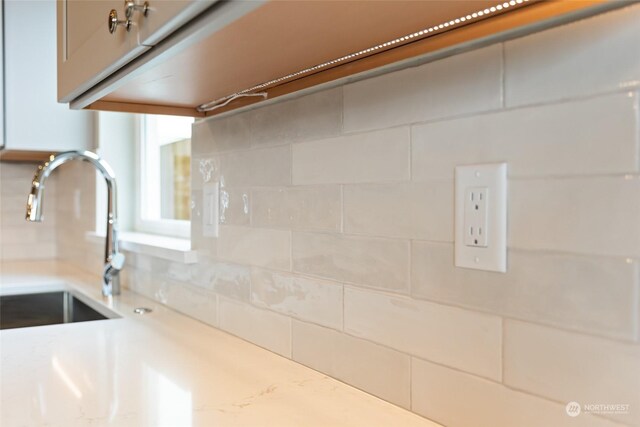 interior details with tasteful backsplash, sink, and light stone counters