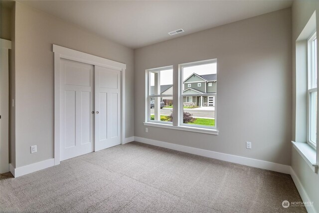 unfurnished bedroom featuring a closet, multiple windows, and carpet flooring