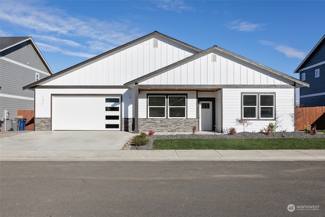 view of front of property with a garage, concrete driveway, board and batten siding, and stone siding