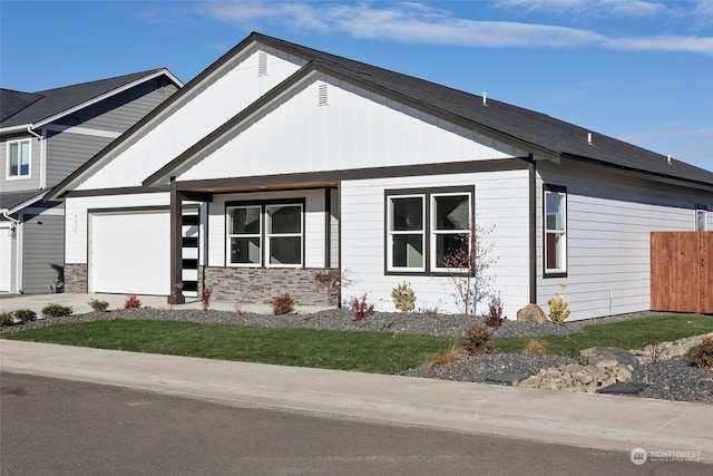 view of front of house with driveway, stone siding, a garage, and fence