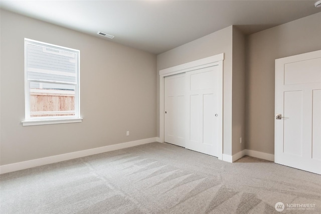 unfurnished bedroom featuring light carpet, baseboards, visible vents, and a closet