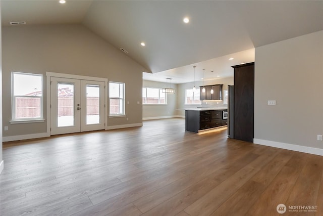 unfurnished living room with light wood finished floors, baseboards, visible vents, and french doors