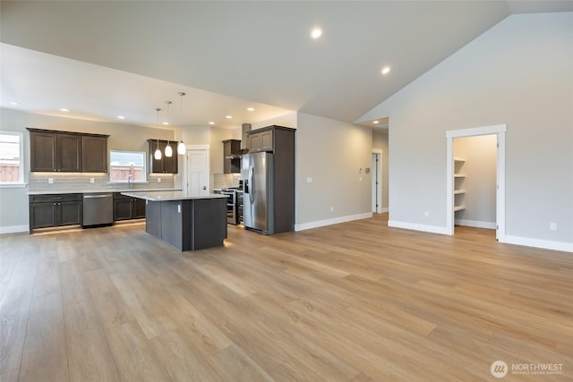 kitchen with pendant lighting, light countertops, appliances with stainless steel finishes, open floor plan, and a kitchen island