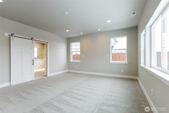 unfurnished bedroom featuring baseboards, a barn door, visible vents, and recessed lighting