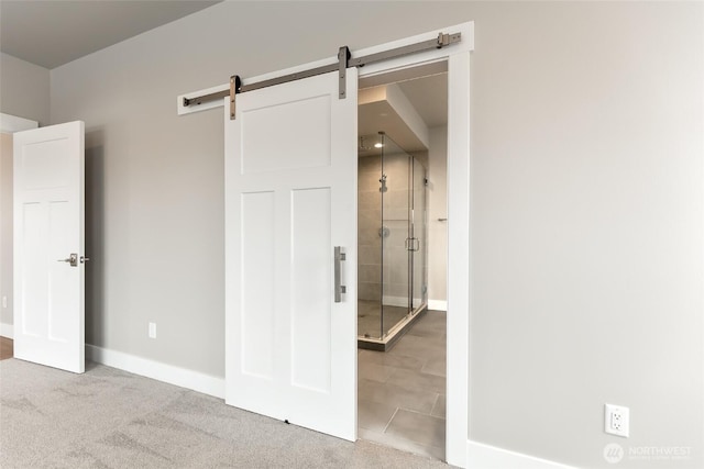 unfurnished bedroom with a barn door, carpet flooring, and baseboards