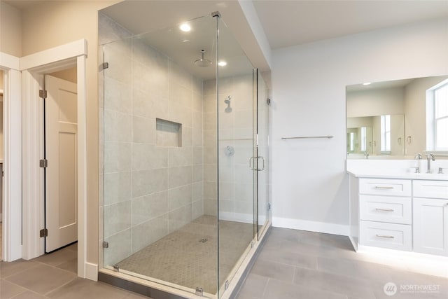 bathroom featuring a shower stall, vanity, baseboards, and tile patterned floors