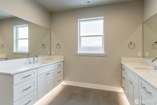 bathroom featuring two vanities, a sink, and baseboards