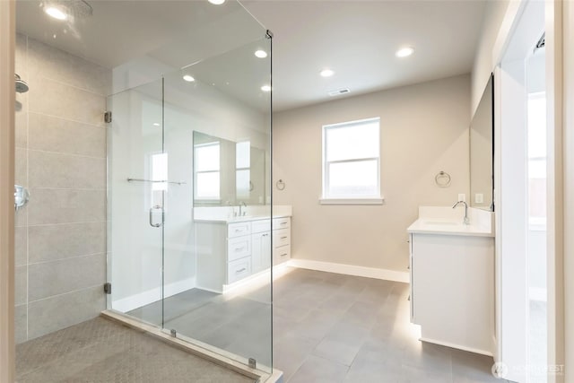 full bath with baseboards, a sink, a shower stall, two vanities, and recessed lighting