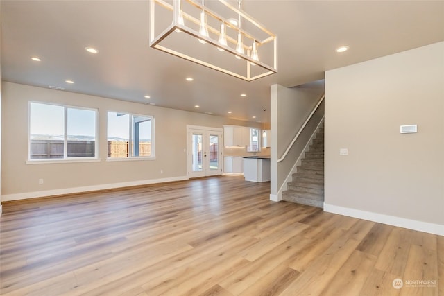 unfurnished living room with light hardwood / wood-style floors and french doors