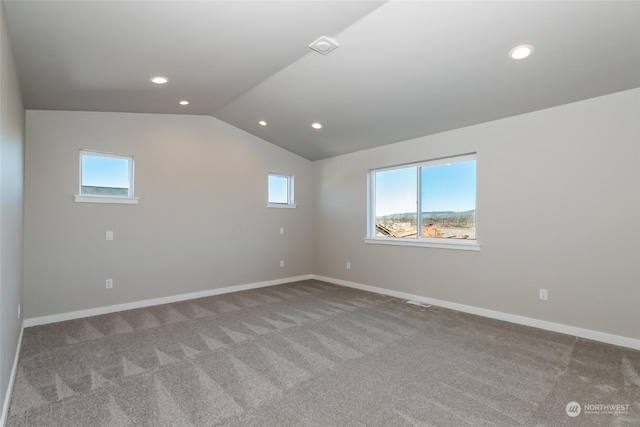 carpeted spare room with vaulted ceiling