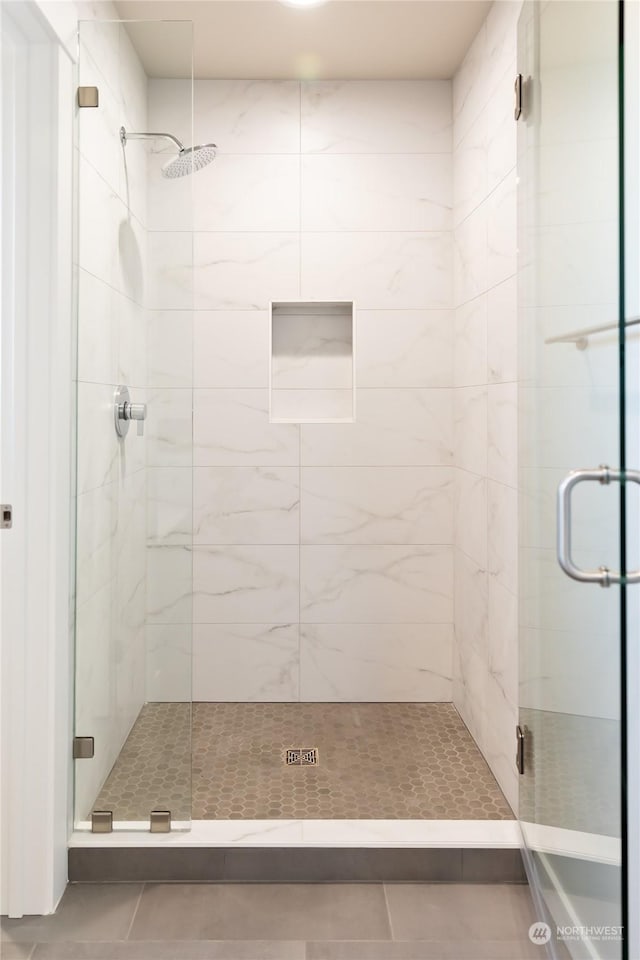 bathroom with tile patterned floors and a shower with door