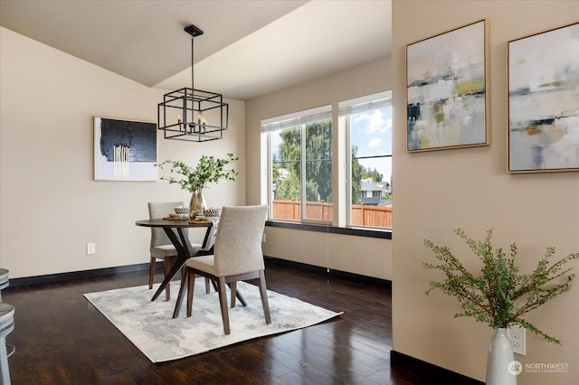 dining area with lofted ceiling, dark wood-style flooring, a chandelier, and baseboards