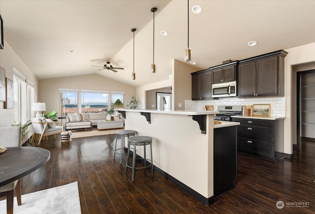 kitchen featuring a breakfast bar area, stainless steel appliances, light countertops, hanging light fixtures, and open floor plan