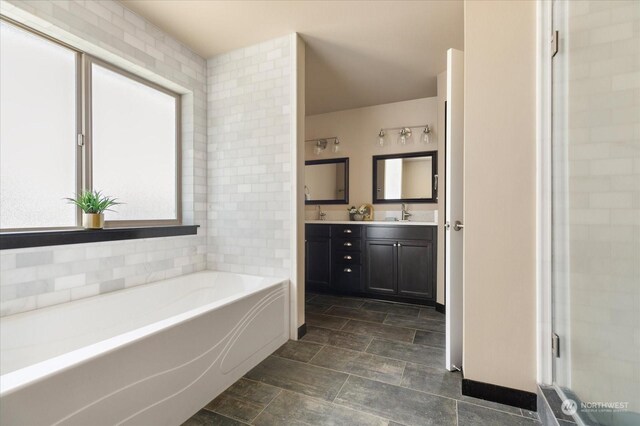 bathroom with a tub to relax in, plenty of natural light, and vanity