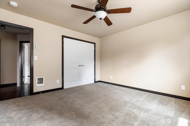 unfurnished bedroom with heating unit, a closet, ceiling fan, and carpet flooring