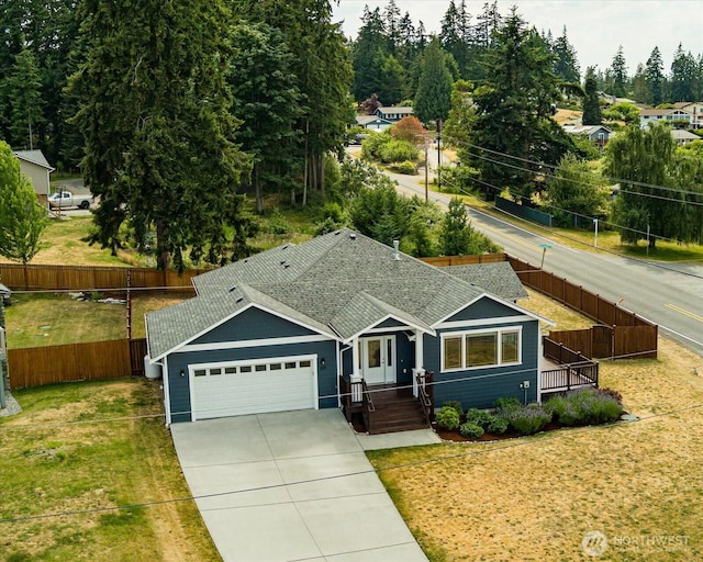 ranch-style home with driveway, a shingled roof, an attached garage, fence, and a front yard