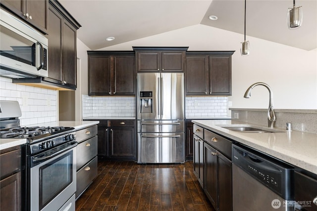 kitchen featuring lofted ceiling, dark brown cabinetry, stainless steel appliances, a sink, and pendant lighting