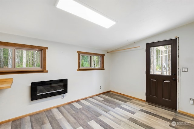 unfurnished living room with lofted ceiling, heating unit, and light hardwood / wood-style floors